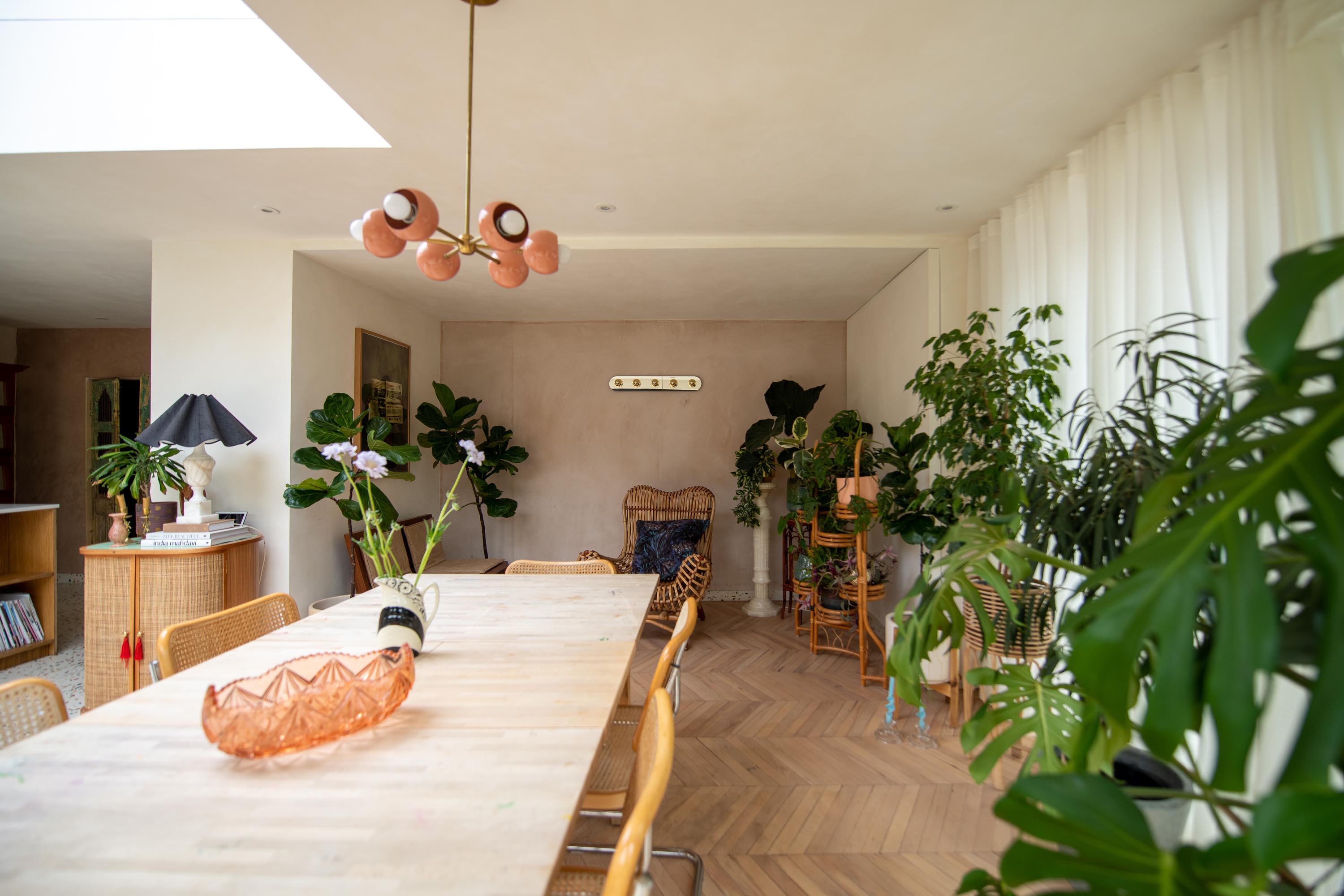 Dining room table inside a kitchen extension, lots of natural light coming from a bespoke roof window and a lot of plants are inside the extension