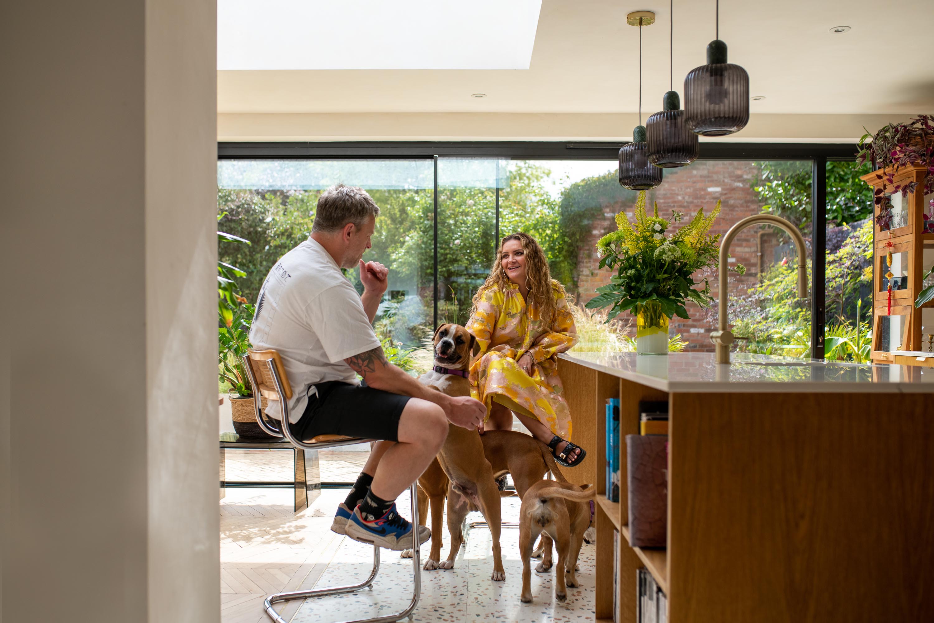 Husband and wife sat laughing underneath a bespoke rooflight. Dog at their feet 
