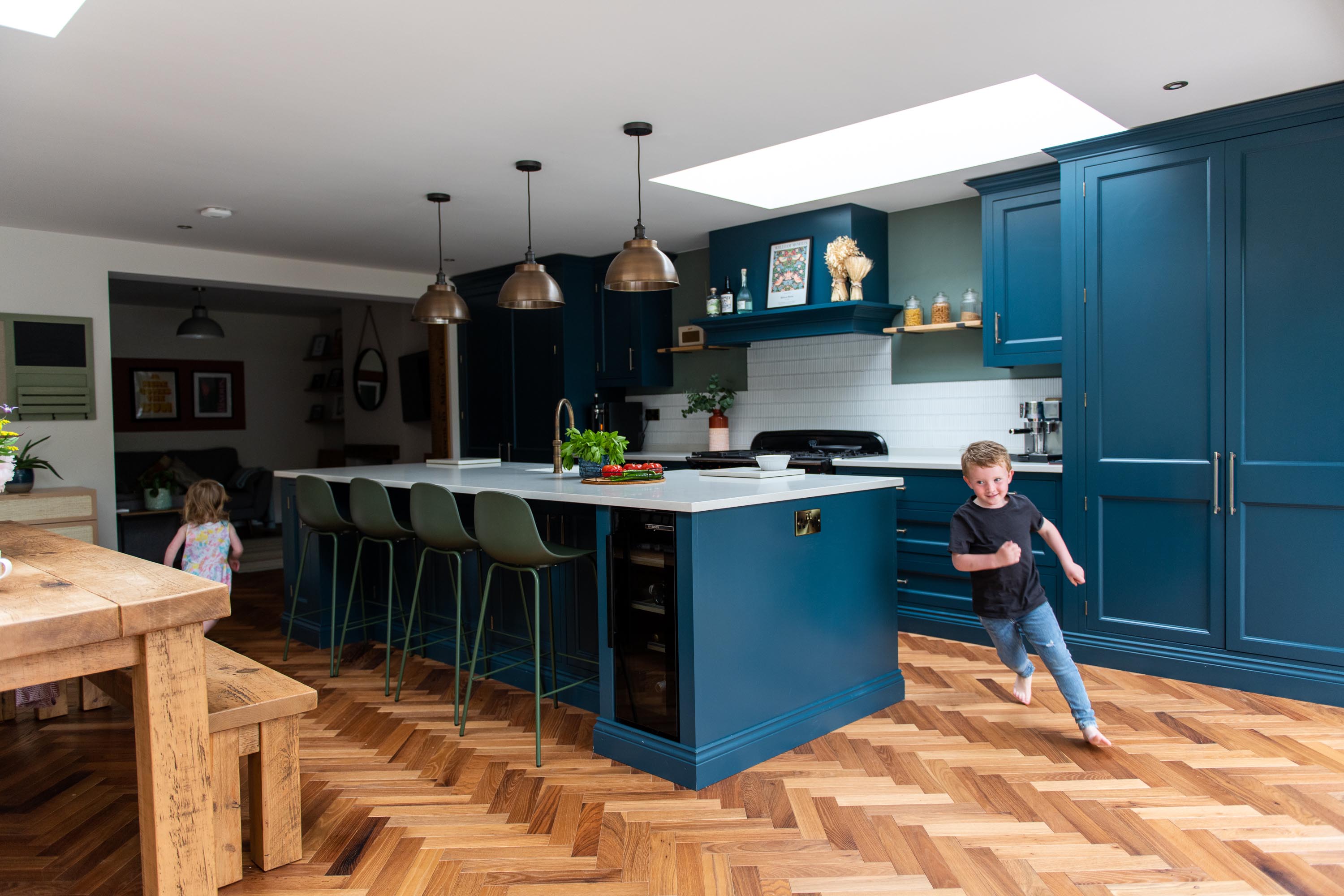 children running around kitchen island under a rooflight 